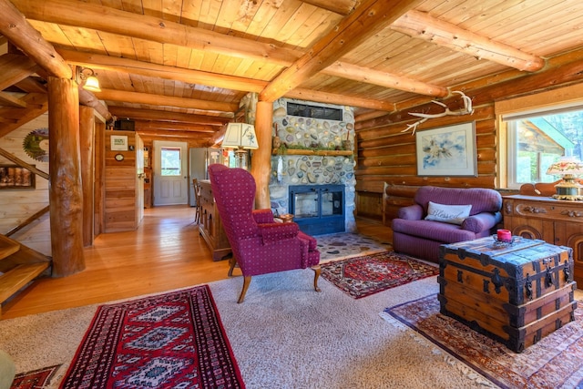 living room featuring wood-type flooring, a wealth of natural light, rustic walls, and a stone fireplace