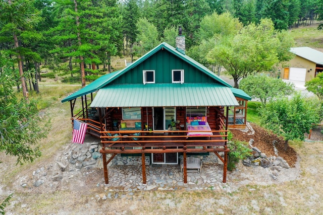 5899 Black Lake Rd, Rexford, MT 59930 - rear view of house with covered porch, a chimney, board and batten siding, log exterior, and metal roof