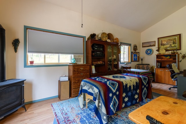 bedroom featuring a wood stove, light hardwood / wood-style flooring, and high vaulted ceiling