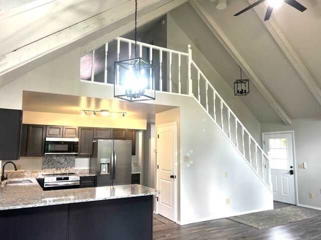 kitchen with dark hardwood / wood-style flooring, appliances with stainless steel finishes, sink, high vaulted ceiling, and decorative backsplash