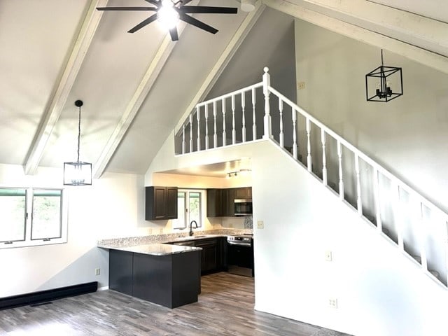 kitchen featuring black range, dark hardwood / wood-style floors, ceiling fan with notable chandelier, kitchen peninsula, and high vaulted ceiling