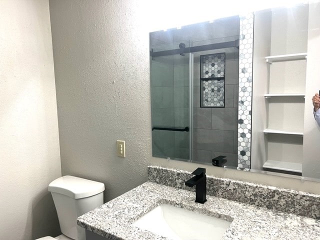 bathroom featuring vanity, toilet, walk in shower, and built in shelves