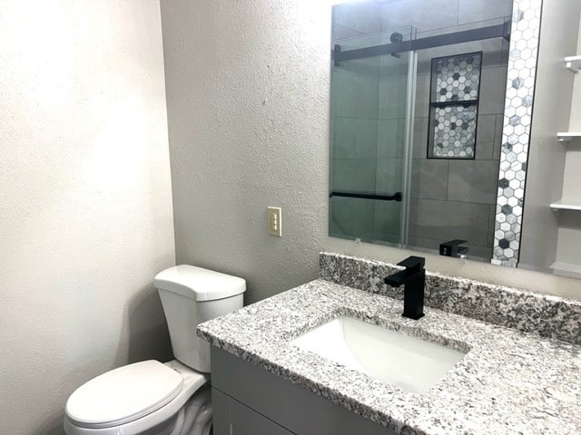 bathroom with vanity, toilet, and a shower with shower door