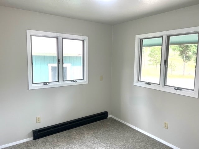 carpeted spare room featuring baseboard heating