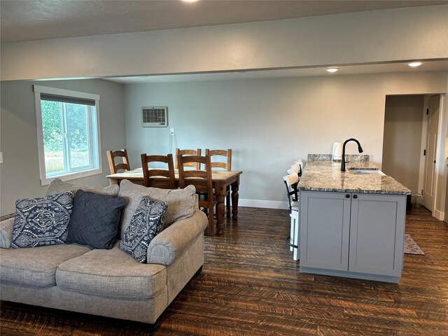 living room with sink, a wall unit AC, and dark hardwood / wood-style floors