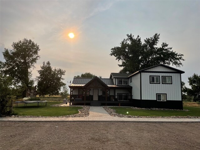 view of front of home featuring a yard, a trampoline, and covered porch