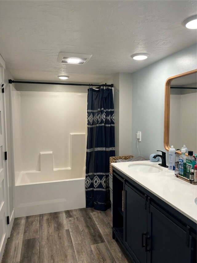 bathroom featuring a textured ceiling, shower / bath combo, hardwood / wood-style floors, and vanity