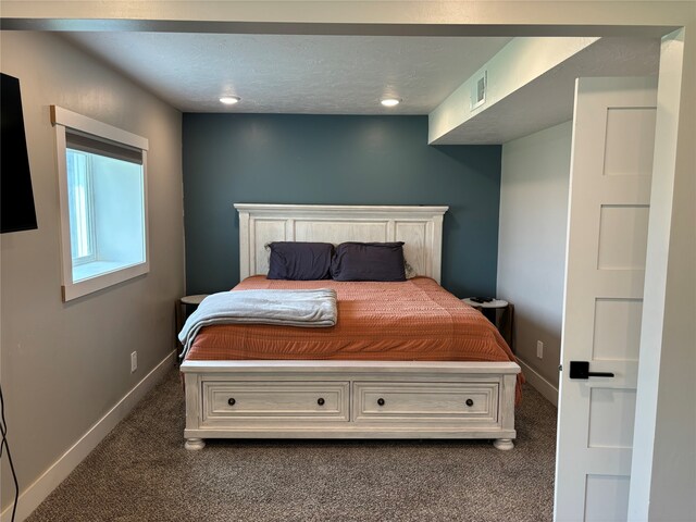 bedroom featuring dark colored carpet and a textured ceiling