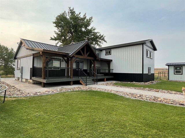 back of house featuring a storage shed, a yard, and covered porch