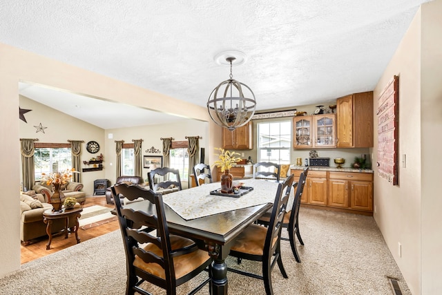 dining space featuring lofted ceiling, a chandelier, and a textured ceiling