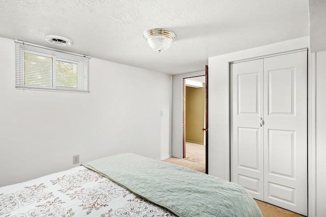 carpeted bedroom featuring a textured ceiling and a closet