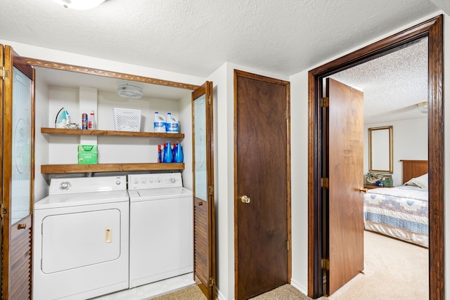 washroom with light colored carpet, washer and dryer, and a textured ceiling