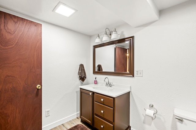 bathroom with vanity, toilet, and hardwood / wood-style floors