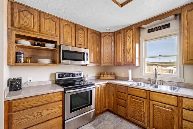 kitchen with appliances with stainless steel finishes, sink, and a textured ceiling