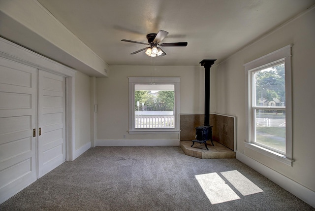 interior space with ceiling fan, a healthy amount of sunlight, and a wood stove