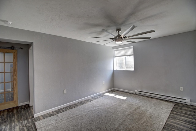 unfurnished room with dark wood-type flooring, a textured ceiling, baseboard heating, ceiling fan, and a barn door