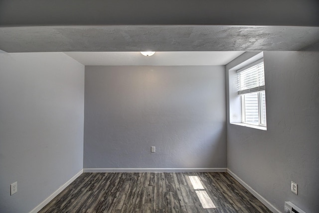 spare room with a baseboard heating unit and dark wood-type flooring