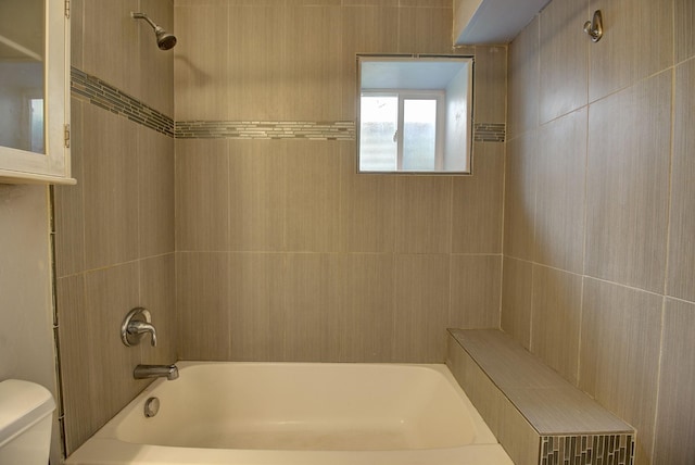 bathroom featuring tiled shower / bath and toilet