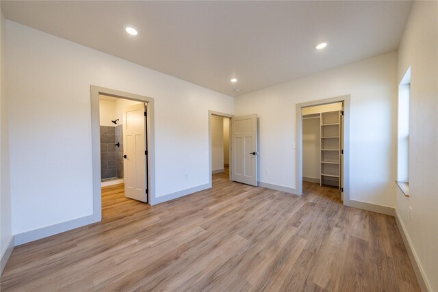 unfurnished bedroom featuring a walk in closet, light hardwood / wood-style floors, and a closet