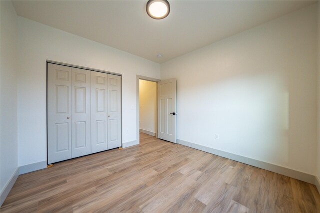 unfurnished bedroom with a closet and light hardwood / wood-style floors