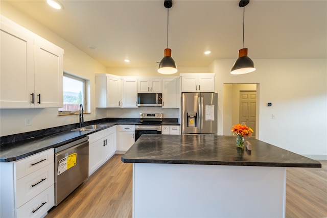 kitchen with a center island, stainless steel appliances, sink, and hanging light fixtures