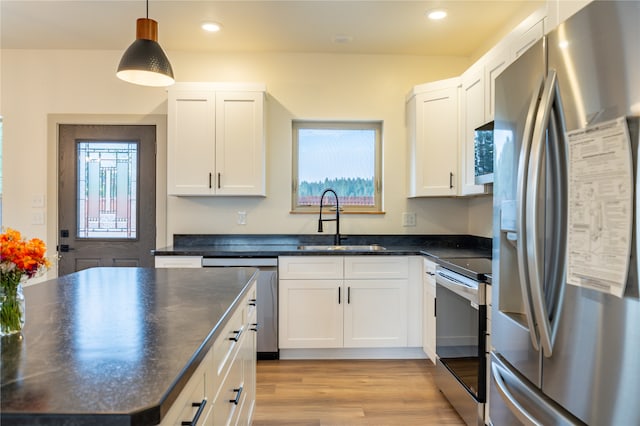 kitchen featuring white cabinetry, light hardwood / wood-style flooring, sink, hanging light fixtures, and appliances with stainless steel finishes