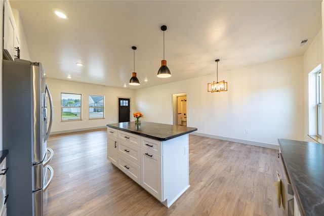 kitchen with hanging light fixtures, a center island, light hardwood / wood-style flooring, stainless steel refrigerator, and white cabinetry