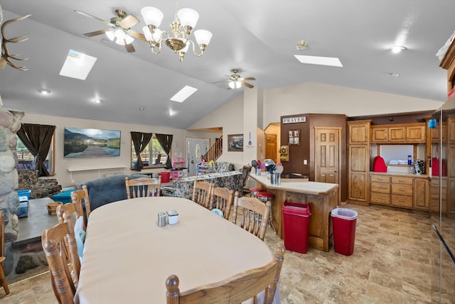 tiled dining room with ceiling fan with notable chandelier and vaulted ceiling with skylight