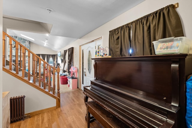 miscellaneous room with lofted ceiling, radiator, and light wood-type flooring