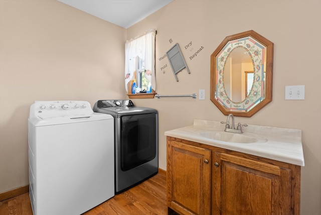 clothes washing area featuring independent washer and dryer, light hardwood / wood-style flooring, sink, and cabinets