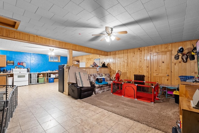 interior space featuring ceiling fan, wooden walls, and light tile patterned floors