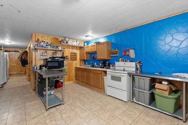 kitchen with sink, wooden walls, white appliances, and light tile patterned floors