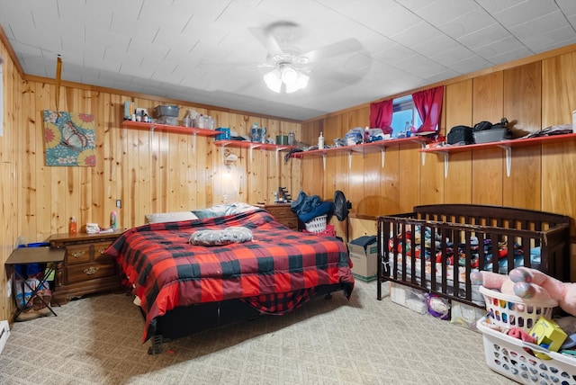 carpeted bedroom with ceiling fan and wooden walls