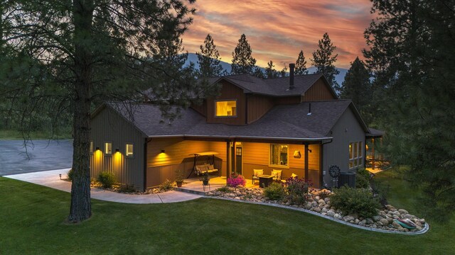 back house at dusk with central air condition unit and a yard