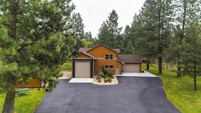 view of front facade with an attached garage, aphalt driveway, and a front yard