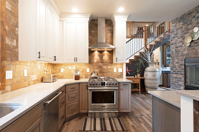 kitchen featuring appliances with stainless steel finishes, wall chimney range hood, dark hardwood / wood-style floors, and white cabinets