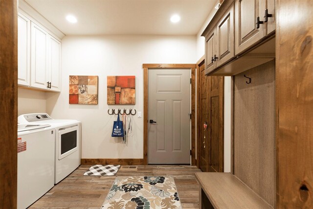 laundry room with light hardwood / wood-style flooring, separate washer and dryer, and cabinets