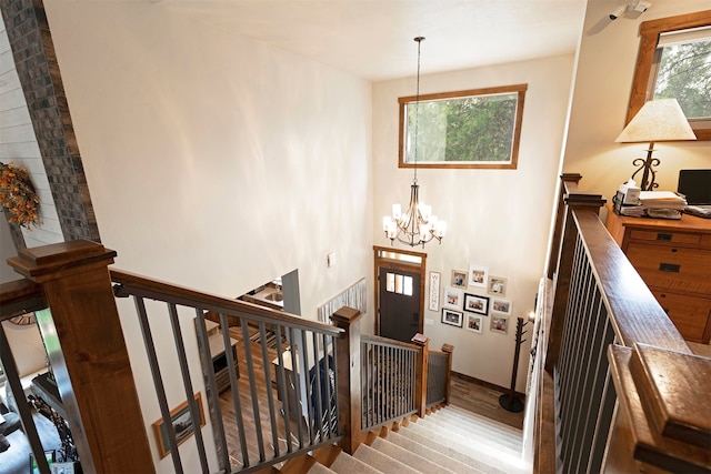 staircase with a notable chandelier and wood-type flooring