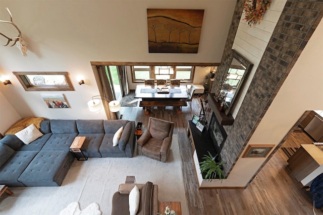 living area with a fireplace with raised hearth, wood finished floors, and a towering ceiling