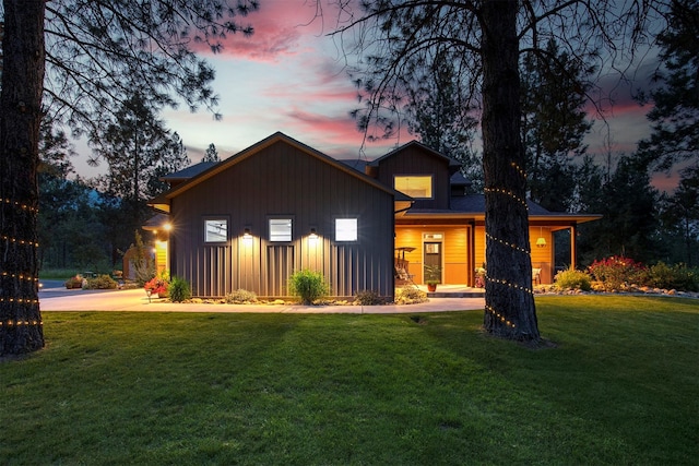 back of property at dusk featuring board and batten siding and a lawn