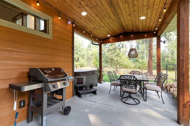 view of patio / terrace with a hot tub, a grill, fence, and outdoor dining space