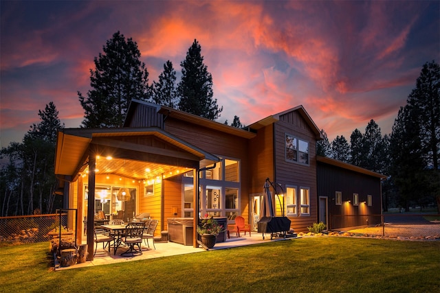 back house at dusk with a yard and a patio area