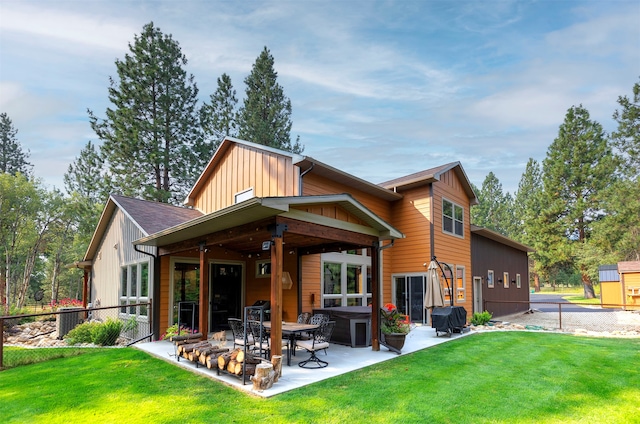 back of house featuring ceiling fan, an outdoor structure, a patio area, and a lawn