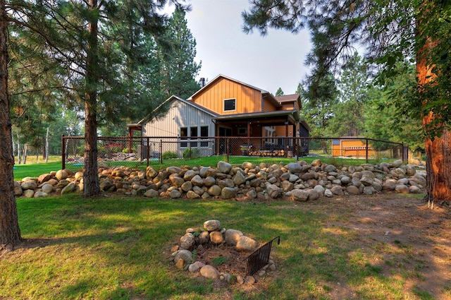 rear view of property featuring a yard and fence