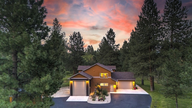 view of front of house featuring an attached garage, aphalt driveway, board and batten siding, and roof with shingles