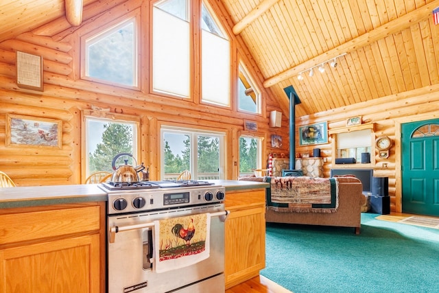 kitchen featuring a wood stove, stainless steel gas range, wood ceiling, log walls, and high vaulted ceiling