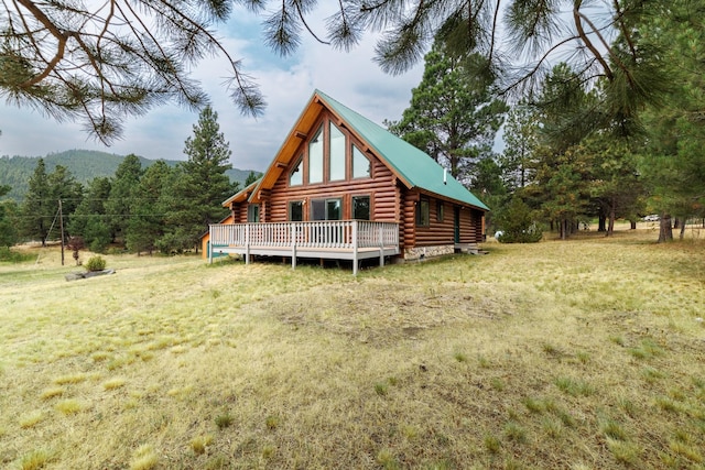 rear view of property featuring a wooden deck, a lawn, and log siding