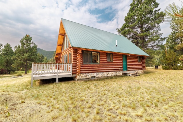 back of house with a wooden deck, log exterior, a yard, and metal roof