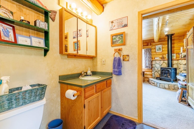 half bathroom with toilet, log walls, wooden ceiling, vanity, and a wood stove