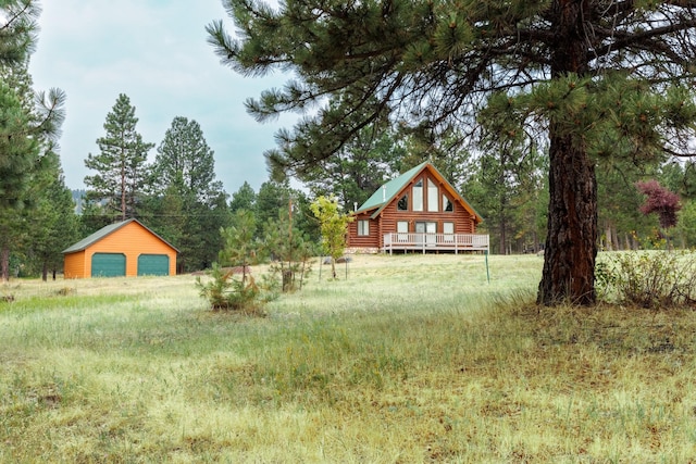 view of yard with an outdoor structure, a detached garage, and a deck